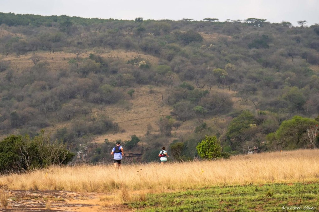 Two runners on an open grassland trail